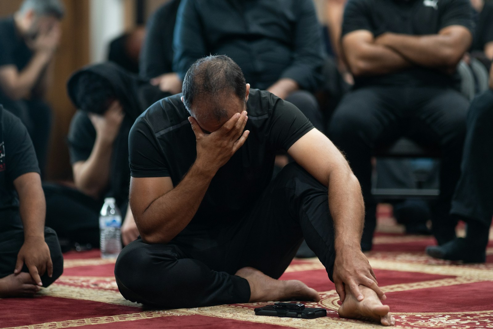 A man sitting on the floor with his head in his hands